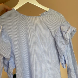 Blåvit blus - Randig blåvit blus med söta detaljer på armarna, den är i barnstolen L men motsvarar en XS