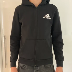 Adidas hoodie Strl:S - Denna fina adidas hoodie är i ett bra skick (obs snören saknas) Den användes förra året ett par gånger och har inte används sen dess. En fin huvtröja som passar dig! Kommer till en väldigt bra pris!