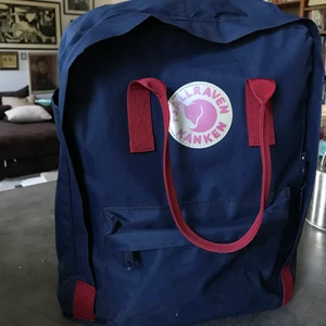 Kånken fjällräven ryggsäck  - Mörkblå Kånken med vinröda detaljer. Vanliga modellen. Välanvänd, gott skick! En knapp är lite rostig och innerfodret upptill är sprucket men utsidan är i gott skick. Sittdel ingår. 