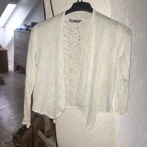 Vit kofta  - Säljer denna tunna,fina bomullskofta från H&M. Den är i bomullsmaterial där framme och i ryggen är det nät med blommor i. Den är använd i bra skick.🦋Jag skulle rekommendera för 10-12 år.