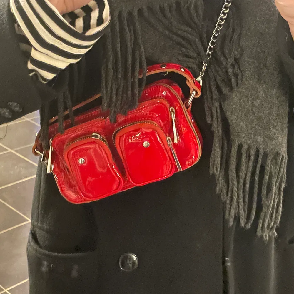 Säljer min skitsnygga väska från nunoo. Den är röd och materialet är lack, det är i den mindre modellen. Det är ett kedjeband men finns även ett rött lite längre band. Använd en del men ändå i bra skick! Köpte för 1200💓. Väskor.