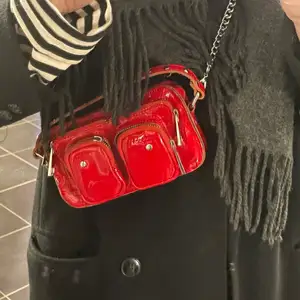 Säljer min skitsnygga väska från nunoo. Den är röd och materialet är lack, det är i den mindre modellen. Det är ett kedjeband men finns även ett rött lite längre band. Använd en del men ändå i bra skick! Köpte för 1200💓