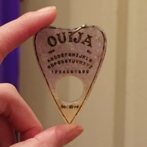 Ouija board halsband - Handgjord Ouija board pendant i resin från Melty Chocolate Moon, köpt under ett konvent för flera år sedan. I gått skick ♥️ lila-aktig med glitter i. Kedja medföljer ej! Sätt på väskan, ha som halsband, örhänge eller nyckelring! 