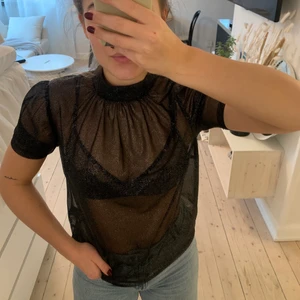 Glittrig meshtopp  - Svartrock glittrig meshtopp från H&M. Kortärmad och med liten krage. Stl. 32. Använd 2 gånger. 