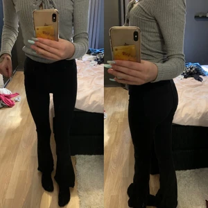 Jeans - Ett par svarta jeans dom är  utsvängda nere vid fötterna. Typ högmidjade