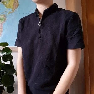 Svart pikétröja - Svart unisex pikétröja med dragkedja och fin silverdetalj.