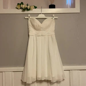 Oanvänd Vit off shoulder klänning strl S - Gummikant på insidan upptill för att klänningen ska hålla sig uppe, även osynlig dragkedja på sidan. Strassdetaljer (kolla sista bilden). Väldigt fin passform. Helt oanvänd i strl S