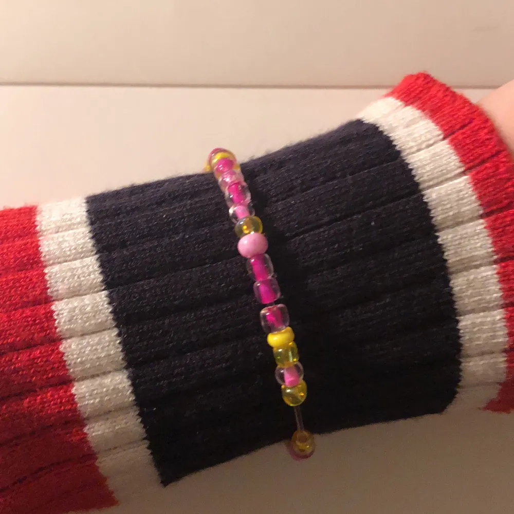 Ett armband i färgerna rosa lila och gul. Armbandet har bindes ringar och karbinhakar. Det är ett hemma gjort armband som jag tycker är super snyggt och fint. 🌸✨. Accessoarer.