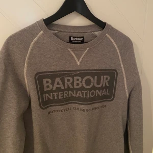 Grå fin Barbour sweater - En grå Barbour sweater i storlek small. Använd ett fåtal gånger och är därmed i fint skick! Funkar både såväl för kvinna som för man.