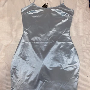 Satinklänning - Säljer denna oanvända satinklänningen från Nelly. Den är i storlek M men skulle säga att den är mer som en S. Jag står för frakten, vill bli av med den fort 💕