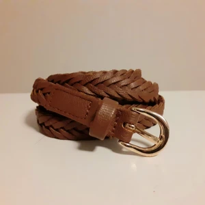 Flätat skärp - Flätat skärp med guldspänne från HM.  Skärpet är 1 cm brett och 100 cm långt och i mycket gott skick. Frakt: 26 kr