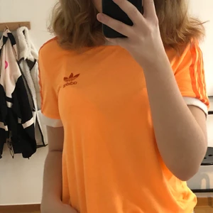 Orange adidaströja - Orange 00’s adidaströja med vit kant på ärmarna. Den säljs för den knappt kommer till användning, använd fåtal gånger. Köpt på en adidasbutik för 400kr. Den är i 36 och är sann i storleken. Pris är diskuterbart