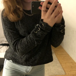 Grå sweatshirt med detaljer på armarna - Jag säljer den här gråspräckliga mjuka tröjan. Den har knytningar på armarna. Tröjan är från FB sister i storleken XS. I bra sick🤎
