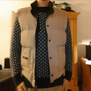 Canada Goose väst, strlk: XL/L - Skick: 9/10. Färg: Khaki.                                       Prisvärd väst för de kallare säsongerna, endast använd ett fåtal gånger av mig under förra hösten 2020. Västen köptes begagnad och därför så medföljer inget kvitto. Passformen är bra för mig som är 193cm lång men den passar även bra för de som är kortare. Iochmed att västen är i storleken XL/L så har den en skön baggy fit.  Hör av er om ni undrar något, exempelvis måtten på den eller om ni vill ha fler bilder.