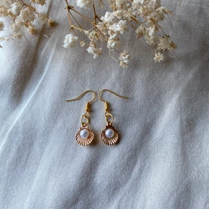 Öronhängen  - Öronhängen i guld färg med en snäcka med en pärla i kostar 20kr plus frakt 13kr totalt 31kr ⭐️⭐️ ⭐️ kostar 20:-  Man får frakt bevis som är bild på packet med din adress samt en bild vid PostNord med kvitto att jag har köpt frimärken och lämnat packet vid fler frågor hör av er ⚡️💗⭐️ man får såklart en överraskning !        Ops viktigt har man inte hört av sig efter man har skrivit att man köper inom 24 timmar så tar vi inte emot er order och produkten kan gå till rea kostar 10kr