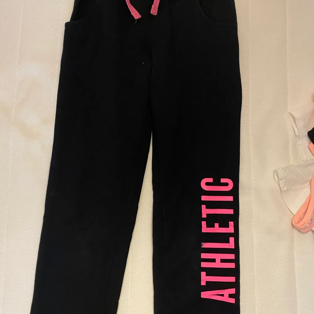 Säljer dessa coola svarta mjukis byxor med en neonrosa text längre ner på ett av benen. Köparen står för frakten och får gärna komma med egna prisförslag! Skriv privat för mer!💕. Jeans & Byxor.