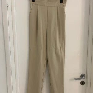Byxor beige - Beiga byxor, hög midja från NAKD