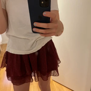 Volang Kjol - En vinröd kjol från bikbok. passar mig som är xs/s. Tror den passar xs-L då den är ganska uttänjbar. Lite högmidjad men det går att vika ner eller ha tröja över.