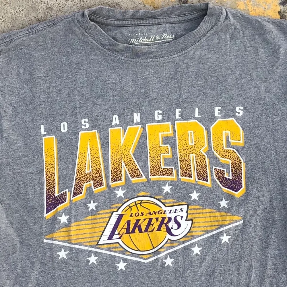 T-shirt producerad av de anrika Mitchell & Ness åt Nba-laget Los Angeles Lakers. Tröjan är i grymt skick, trycket är dock lite slitet men det är inget som stör helheten av tröjan. riktigt najs t-shirt till sommaren. Tröjan är S men skulle snarare säga att det är en Xs. Det är bara att skriva om du undrar något! 💛💜. T-shirts.