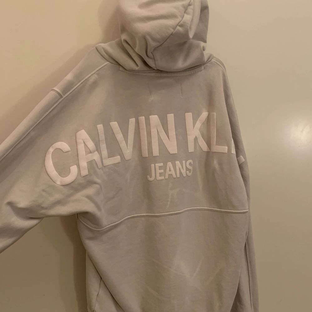En Calvin klein hoodie i storlek M med ett tryck på ryggen. Den är i färgen grå och är lite vitspräcklig så den får en snygg marmor effekt. Huvtröjor & Träningströjor.