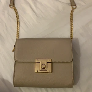 Beige väska - Säljer min beiga väska med guld som jag inte var vart den är ifrån, den har ett litet fack inuti. Den är i fint skick och använd kanske 3-4 gånger.