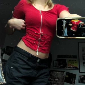 Tajt röd topp med dragkedja - Jag säljer denna snygga toppen som är perfekt för fester och sitter jättesnyggt! Anledning att jag vill sälja är eftersom att jag inte gillar färgen rött och itne tycker den passar med min hudton, har därför bara använt den en gång och sedan ångrat mitt köp för att jag inte gillar färgen. Den har en väl fungerande dragkedja och snygga detaljer på axlar och framför dragkedjan. Den är i perfekt skick och redo att användas!❤️