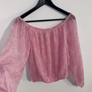 Off shoulder tröja str 38 - Säljer denna off shoulder tröjan från nakd. Den är lite genomskinlig vilket gör att den är perfekt när det är varmt ute då den är sval. Ljusrosa med vita blommor. Pris 60kr + frakt🌸