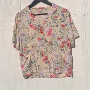 Blus från Åhléns S - Blommig blus med två fickor framtill. I mycket bra skick, bara andvänt fåtal gånger. Storlek S. 