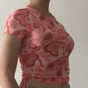 Hjärtlig Mesh topp - Rosa mesh topp med hjärtan från shein. Nyligen beställd, därtill aldrig använd. längden e dock justerbar då dragsko snörning finns vid varsin sida om midjan för längre alternativ, för övrigt mer av en magtröja. Stl L, enligt mig XS-M då den är mindre i storleken än ordinarie. Står btw ej för frakt! 