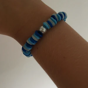 Preppy jewelry blue - Jag säljer ett handgjort armband i färgerna mörkblå, ljusblå och vit med en rund vi pärla i mitten. 