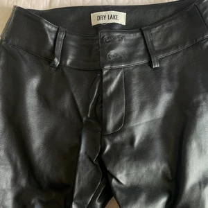 Bootcut fake läder byxor  - Tyvärr sönder på båda siderisk där bak ser likadant ut på båda sidorna men har sytt igen slarvigt går att ta bort å sy snyggare 