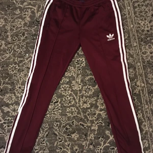 Adidas originals - Vinröda Adidas originals i storlek Small, superfina! Knappt använt dom, och tvättade så klart ;) dom är tyvärr lite för små i storleken för mig, har dragkedjor nertill i benen och på fickorna, dom här är såå snygga och jättesköna! Nypris ligger dessa fortfarande runt 600-700kr i butik. 