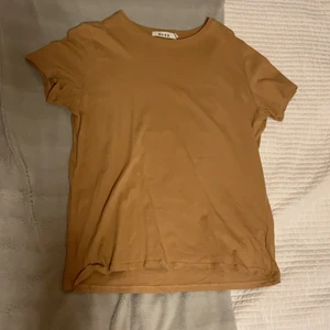 Beige T-shirt - Beige T-shirt från NA-KD, säljer då den inte längre är min stil. Färgen gör sig inte riktigt rättvis på kameran (den är lite ljusare än på andra bilden).