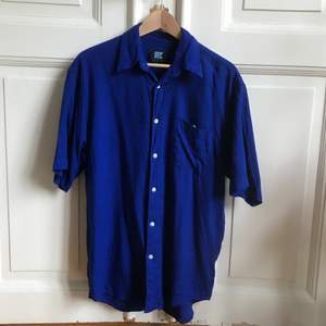 Intensivt blå skjorta i 90-talsmodell. Gissar att den är i bomull. Jag är strl XS/S och har haft den som oversize - tror även den skulle vara OS på M :) superskön och sval på sommaren!