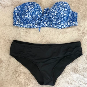 Bikiniset  - Fint bikiniset bestående av en överdel med rosett framtill och guldspänne baktill samt en enkel svart trosa med krås baktill (se bild). Det går att köpa överdel samt underdel separat om så önskas (15kr styck). Setet är använt flera gånger men i bra skick. Överdelen är storlek 40 och underdelen storlek 38. Tvättas självklart före sändning. 