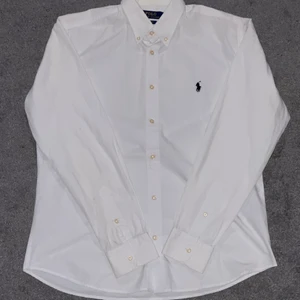Polo Ralph Lauren (vit) skjorta - Vit skjorta i 8/10 skick! Slim fit modell i bra skick. Sitter som en M och kan båda va knäppt och uppknäppt.👍🏼