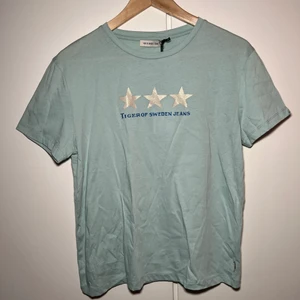 T-shirt Tiger of Sweden (S) - Helt ny t-shirt från Tiger of Sweden. Lappen sitter kvar. Den är ljusblå/turkos eller vad man nu kallar den här färgen.. 🤔 Fick den av svärfar, som aldrig lyckas köpa kläder som passar min stil, i julklapp. Det är iallafall fint att han försöker! Känns onödigt att den ska ligga i min garderob och ta upp plats!