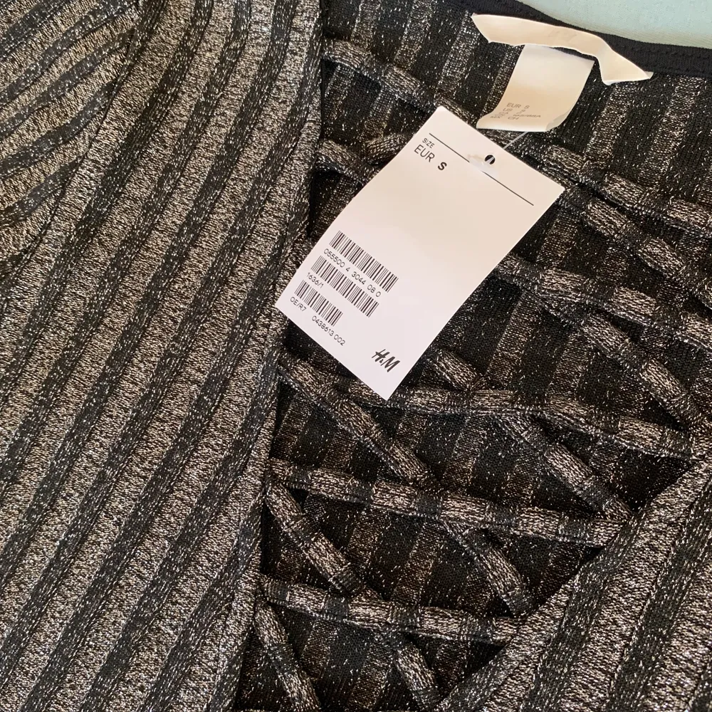En helt oanvänd svart/grå glittrig tröja med snörning. storlek S men passar M också, taggen sitter kvar. 100kr om vi möts i Kalmar, annars 120kr.. Tröjor & Koftor.
