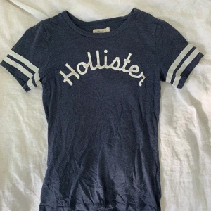 Hollister T-shirt stl S - En väl använd Hollister T-shirt i storlek S. Den är i fint skick på sättet att det är inga lösa sömmar, hål etc. Däremot nopprig och lite ”skavd” på Hollister texten i fram. Köparen står för frakten