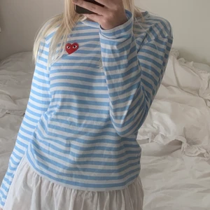 Comme Des Garçons Play långärmad tröja - Blåvit-randig långärmad tröja från Comme Des Garçons Play. Tröjan är knappt använd och är därför i utmärkt skick. Nypriset är omkring 1 500 kr