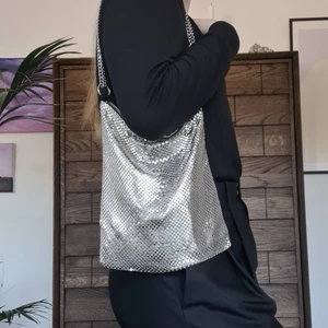 Metal bag - Silvrig metallväska, funkar både som axelväska och crossbody, hand för storleksreferens