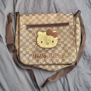 Hello Kitty axelremsväska - Inte officiell Hello Kitty merch! Väskan är ca 30x25 cm stor och bandet kan justeras. Det finns typ 4 fack. Bara att skriva om ni vill ha mer bilder! 