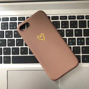 Säljer ett helt nytt mobilskal till en iPhone 6/7/8💘 || Skalet är i en mörkare beige färg med ett guldigt hjärta på || Osäker på vilket material det är i, men liknar plats fast det är mjukare (böjbart)✨ || Köparen står för fraktkostnaden på 12kr📦