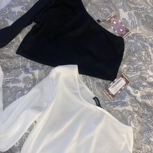 One Shoulder tröjor - 1 svart och 1 vit one shoulder croppade tröjor från boohoo i ribbat material. aldrig använda med lapparna kvar, skriv för egna bilder! 💛 tröjorna är i storlek 38 men skulle mer säga 36! 50kr/st eller båda för 120 inklusive frakt