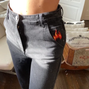 Coola byxor med eld - Säljer dessa coola svarta jeansen med broderad eld på fickan🥵 aldrig använda🥰 storlek 34 men passar även 36❤️