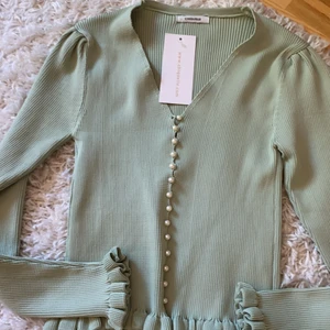 oanvänd supersöt tröja/blus - En jättefin tröja/blus med pärlknappar och volang nertill. Oanvänd med prislapp kvar. Storlek: OneSize