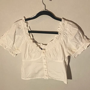 Topp från GinaTricot - En oanvänd topp som är vit, knapparna går att knäppa upp och det är stretch ibak, kan användas både som en off scoulder och som en ”t-shitt”