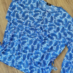 Blå mönstrad blus - Blå mönstrad blus  Strl. XL Knyt detaljer i nedre kant och resår detalj vid ärmslut.