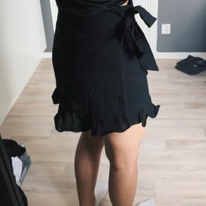 Svart volangkjol - Svart kjol strl L (men mer som M) med knytning i sidan, och dragkedja på andra sidan 