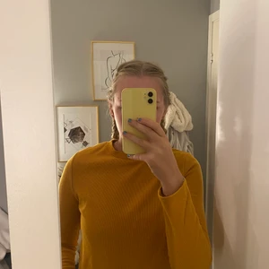 Långarmad - En långarmad tröja från Primark med tre silvriga knappar i axeln på tröjan. Den är senapsgul i färgen men lutar mer åt orange.